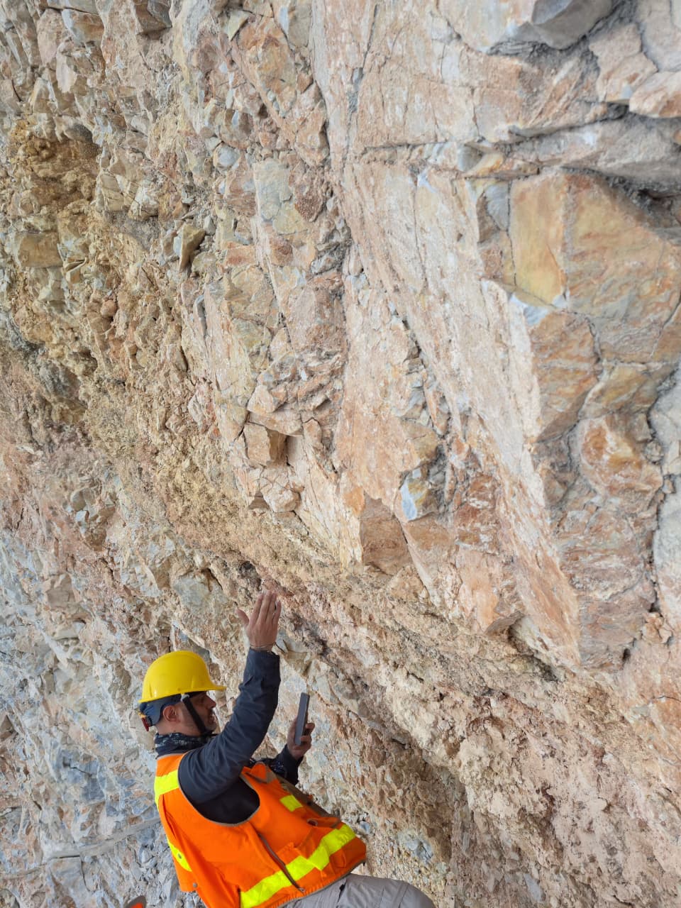 Geólogo de Mineral Vector inspeccionando un afloramiento carbonatado durante trabajo de campo.